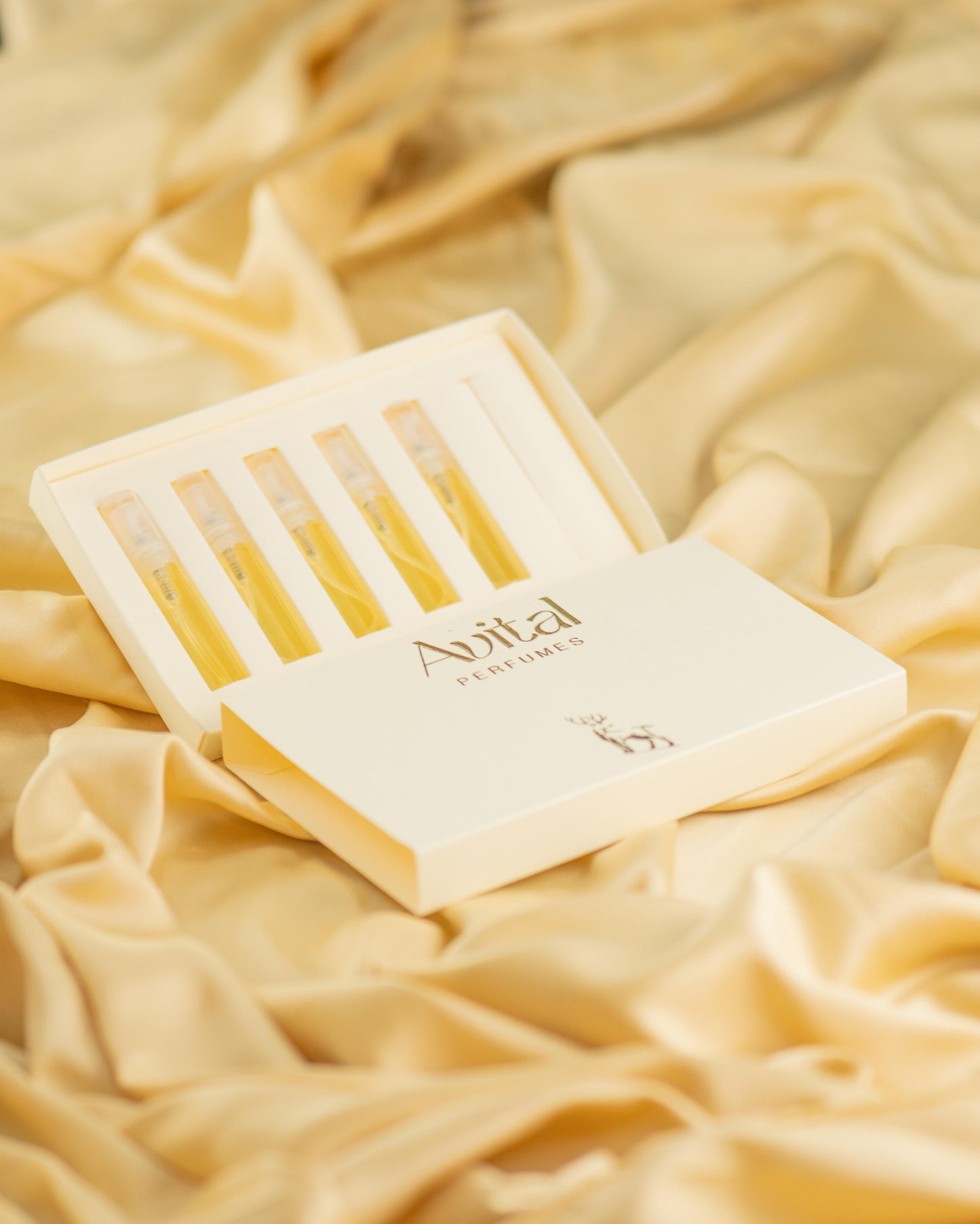 Open tester box of Avital Perfumes featuring five tester vials, elegantly displayed on soft golden satin fabric, emphasizing luxury and sophistication